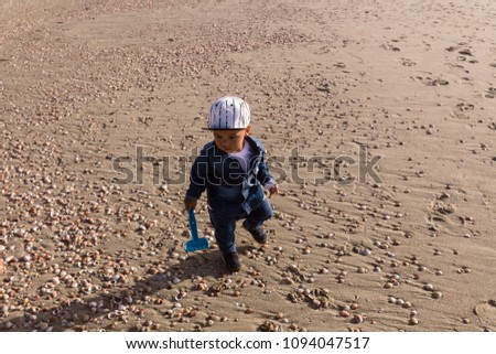 Young toddler having fun by himself at an urban beach on a sunny day.