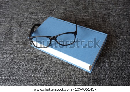 Blue hardcover and a pair of reading glasses