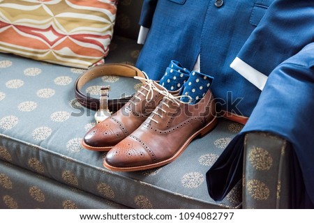 Men's leather new brown shoes closeup still life on blue couch with socks, watch, suit for getting ready wedding or interview preparation in room Royalty-Free Stock Photo #1094082797