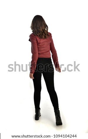 full length portrait of brunette girl wearing red leather jacket, black jeans and boots. standing pose, isolated on white studio background. Royalty-Free Stock Photo #1094104244