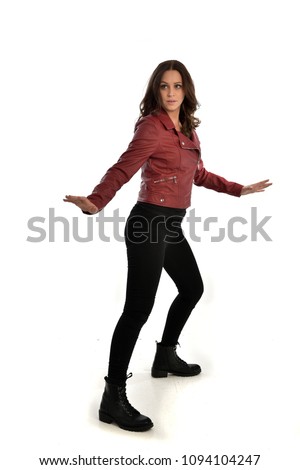 full length portrait of brunette girl wearing red leather jacket, black jeans and boots. standing pose, isolated on white studio background.
