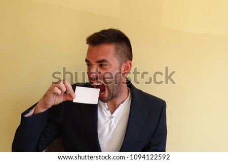 handsome man about to bite an empty white card, business concept, angry boy