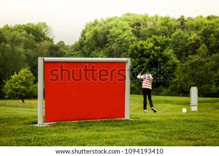 Golf course activity with a mock-up billboard area. Long shot. 