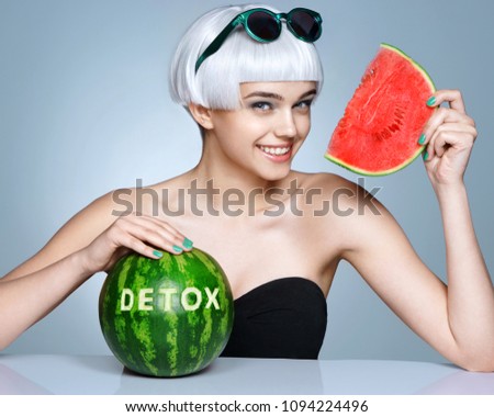 Happy girl with ripe watermelon. Photo of smiling girl in sunglasses on blue background. Detox concept