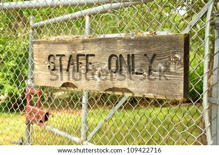 wooden warning sign attached to the metallic fence