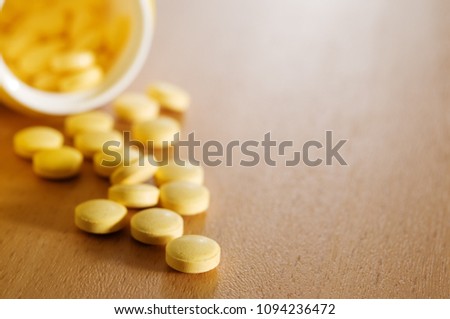 Pills and plastic bottle on the wooden table. Focus on foreground.