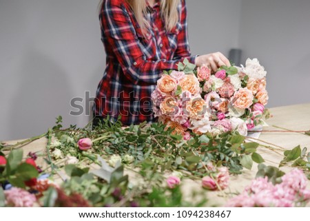 Female florist. Floral workshop - woman making a beautiful flower composition a bouquet. Floristry concept