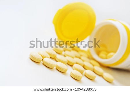 Pills and plastic bottle on the white table.