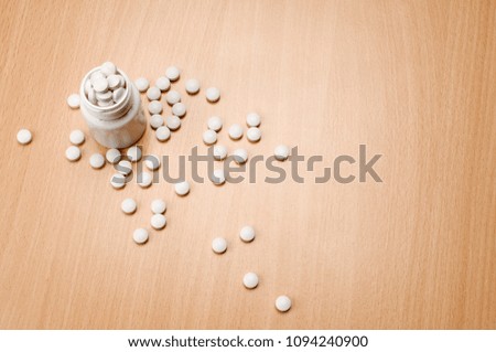 Pills and plastic bottle on the wooden table.