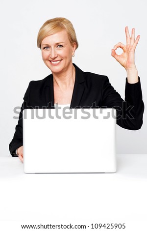 Happy businesswoman gesturing okay sign isolated against white background