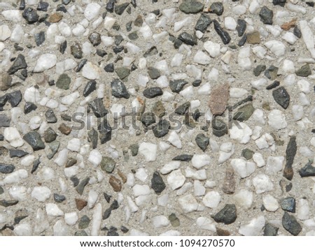 Grey and white little stones in cement