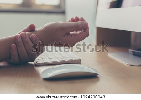 Hand of a businessman with a wrist injury of his own working a computer. Office syndrome concept