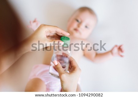 Mother makes massage for happy baby, apply oil on the hand, with white background