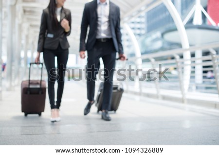 blurred background of businessman and businesswoman walk together with luggage on the public street, business trip concept and copy space for text