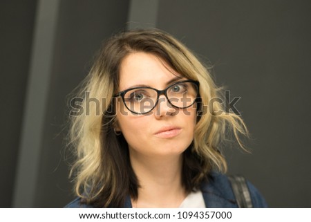 portrait of a young beautiful girl in glasses on a gray background