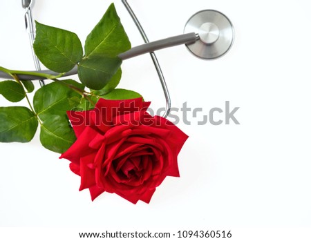 Stethoscope silver and grey with red rose with green leaves on a white background, top view