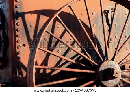sunlight and shadow on rusted iron wheel