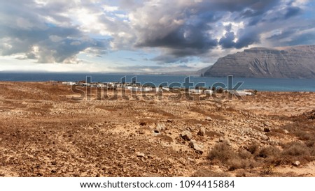 Scenic view of Pedro Barba village under a sky with clouds. Ocean on the background. La Graciosa, Lanzarote, Canary Islands, Spain.