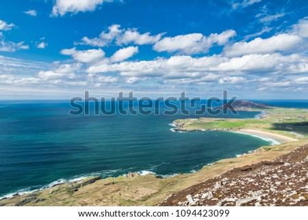 This picture was taken from the Urris mountatins in Donegal Ireland looking out towards the Atlantic ocean. There was a blue sky with white fluffy clouds and a turquoise ocean.