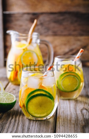 A refreshing summer ice-cold drink. White wine sangria in glass with lime, lemon and orange on a wooden rustic background