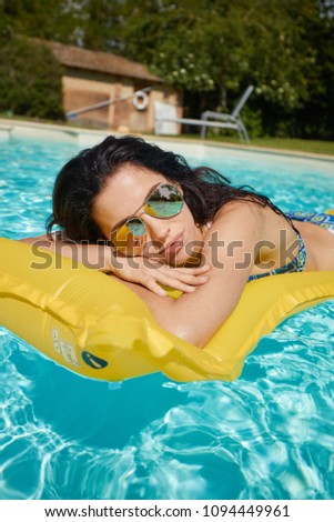 Woman relaxing on donut lilo in the pool at private villa. Inflatable mattress. Summer holiday idyllic. 