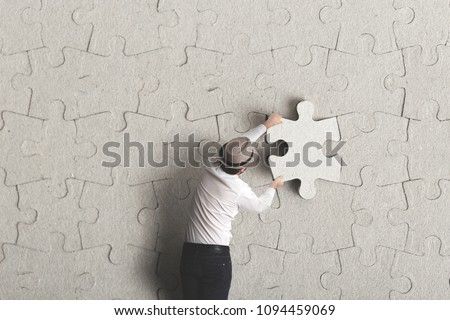 man places last piece of puzzle surreal concept Royalty-Free Stock Photo #1094459069
