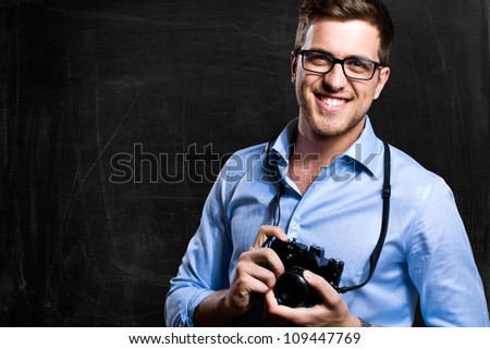Smiling photographer in front of a blackboard Royalty-Free Stock Photo #109447769