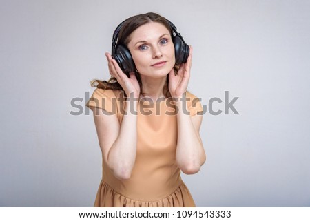 I like listening to music on headphones. Portrait of beautiful brunette girl on white background listening music with headphones. She is standing right in front of the camera smiling and looking happy