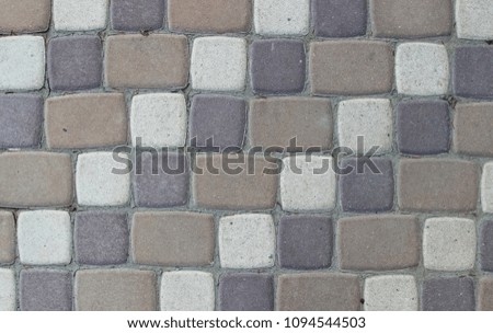 Texture of pavement made of paving tiles of three colors with cement between tiles