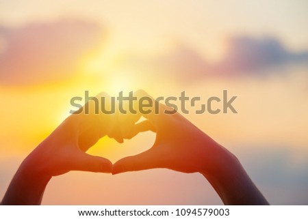 Hands make in heart form love with silhouette at sun set background