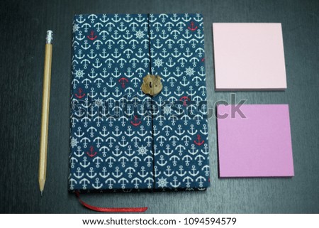 Blue notebook with pencil and color note papers on the black table in the office.