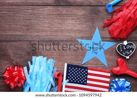 American flag, rubber balloon and paper star with inscription Happy Independence Day on wooden table