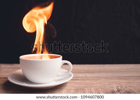 White coffee cup with a fire inside a glass is placed on a woode