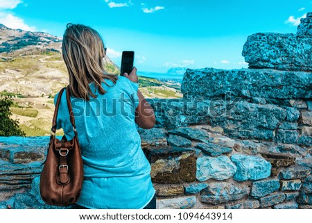 Woman taking photos of the scenery of Segesta at the Greek Theater in Sicily island, Italy