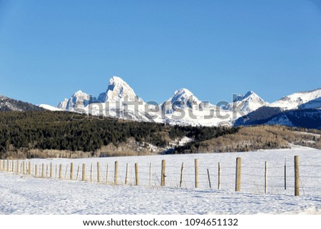 A barbed wire fence on Idaho farmland to keep livestock inside, in front of the Teton mountains 