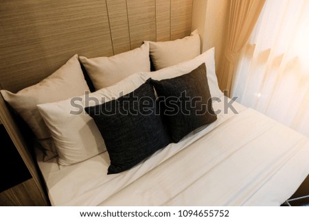 Bed maid-up with clean white pillows and bed sheets in beauty bedroom.