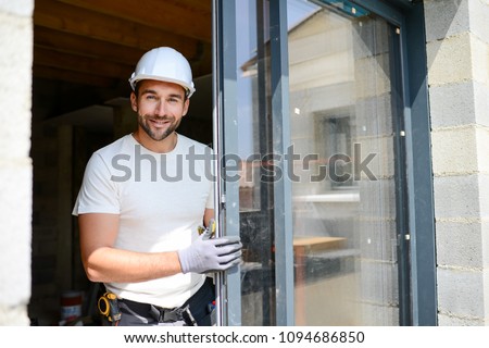 handsome young man installing bay window in new house construction site