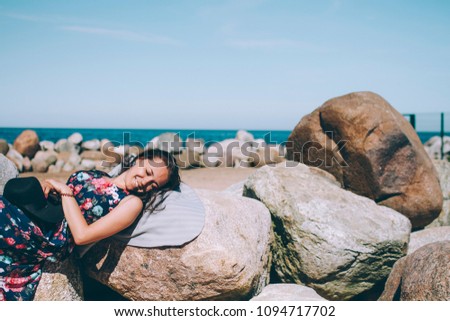 Girl lies on a rock on the beach smiling