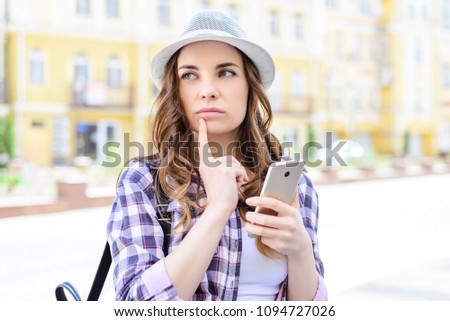 Unknown satellite adventure idea solution concept. Close up portrait of pretty thoughtful student trying to concentrate and find the right way to place of destination touching chin holding mobile