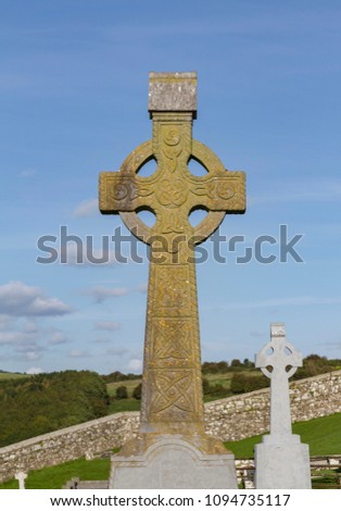 In rural Ireland, graves are often marked with Celtic crosses. This one in Western Ireland shows signs of age and is carved with trefoil knots and celtic knots. Royalty-Free Stock Photo #1094735117