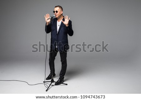 The mid age Showman interviewer with emotions. Young elegant mature man holding microphone against white background.