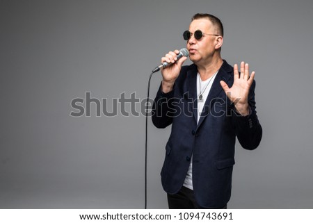 The mid age Showman interviewer with emotions. Young elegant mature man holding microphone against white background.