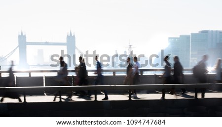 London, UK. Blurred image of office workers crossing the London bridge in early morning on the way to the City of London. Tower bridge at the background