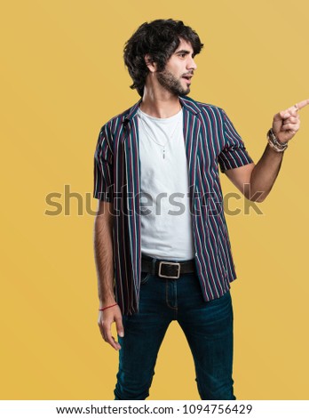Young handsome man pointing to the side, smiling surprised presenting something, natural and casual