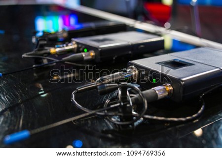 Three wireless microphone transmitter and three wireless microphone reciever on black table in tv studio