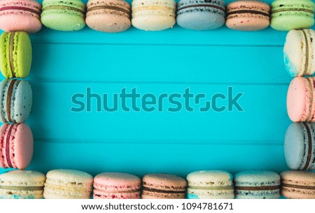 Frame of macaroons on a turquoise wooden background, almond cookies in the form of a postcard. Copy space