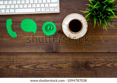 Customer service concept. Concact information. Phone, message, email signs on office work desk with computer on dark wooden background top view copy space