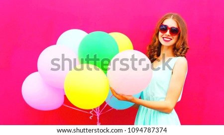 Pretty girl with an air colorful balloons having fun in summer over pink background