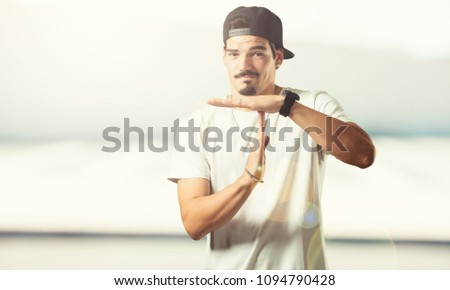 Young rapper man tired and bored, making a timeout gesture, needs to stop because of work stress, time concept