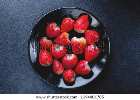 Top view of fresh red strawberries. Fruit arranged on a black plate, ready to eat.